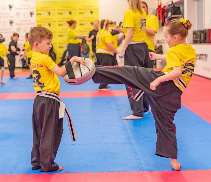 Two young Ninjas students practising pad kicks
